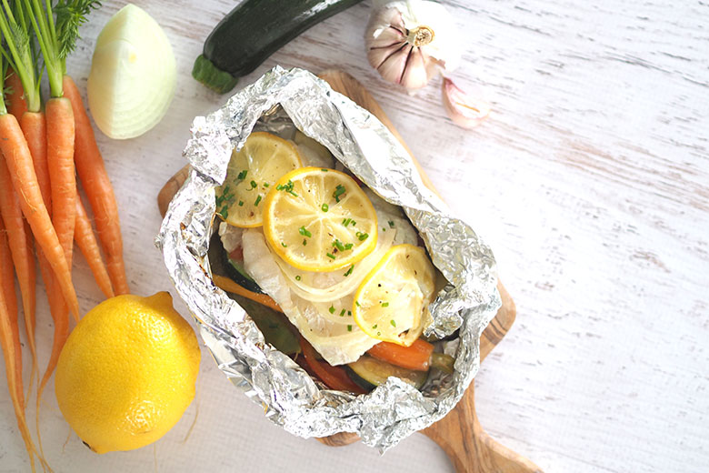Scrumptious flaky baked fish with vegetables, deliciously light and fresh. From start to finish, you will have this on the table in less than 30 minutes.