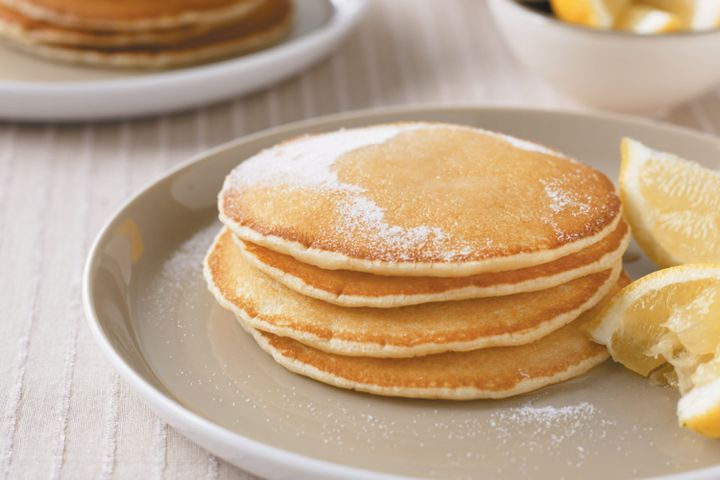 powered sugar on a stack of four pancakes with lemons