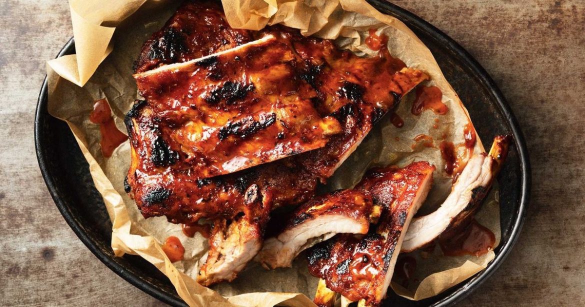 glazed pork ribs straight out of the grill, placed on paper on a steel plate